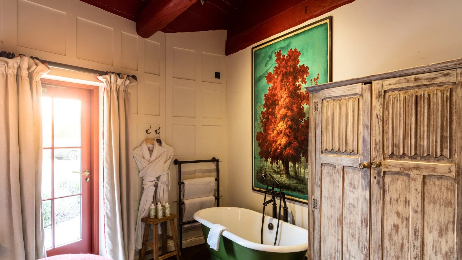 The Double Red Duke — a panelled bathroom with a green roll-top bath