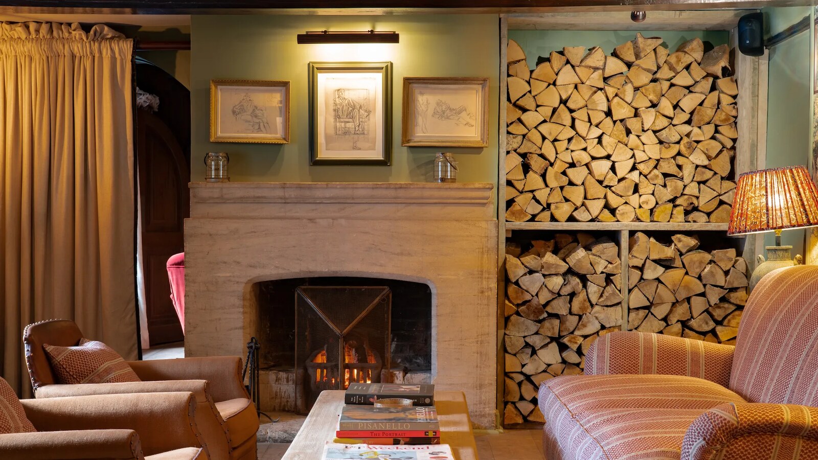 The Double Red Duke — a sitting room with open fire, log store and armchairs