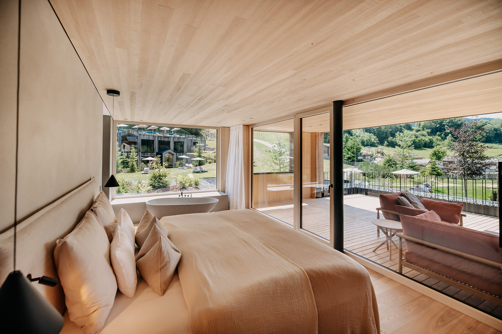 Naturhotel Forsthofgut — a wood-lined bedroom opening to a mountain-view terrace