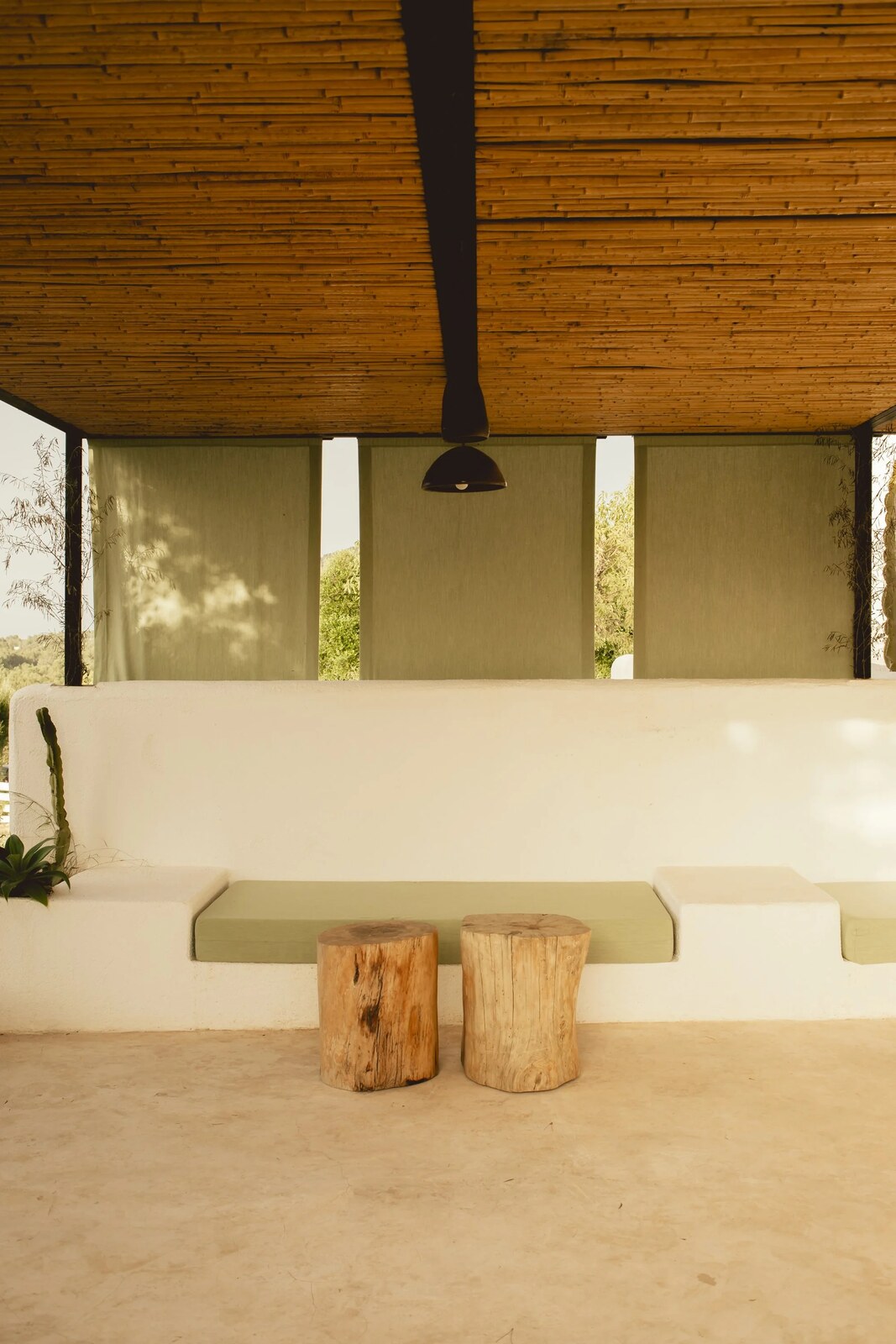 Can Domo &mdash; a shaded outdoor lounge with green linen seating beneath a cane ceiling