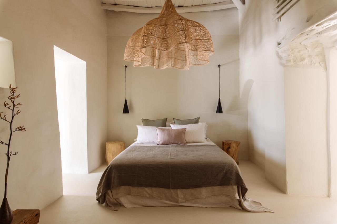 Can Domo &mdash; a whitewashed bedroom with a woven rattan pendant