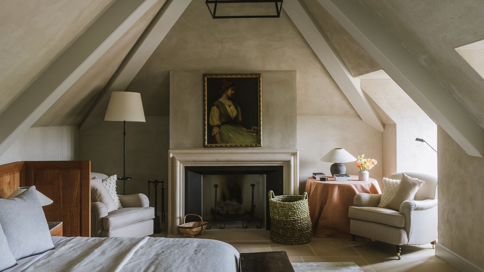 An attic bedroom with exposed beams and a lit fireplace