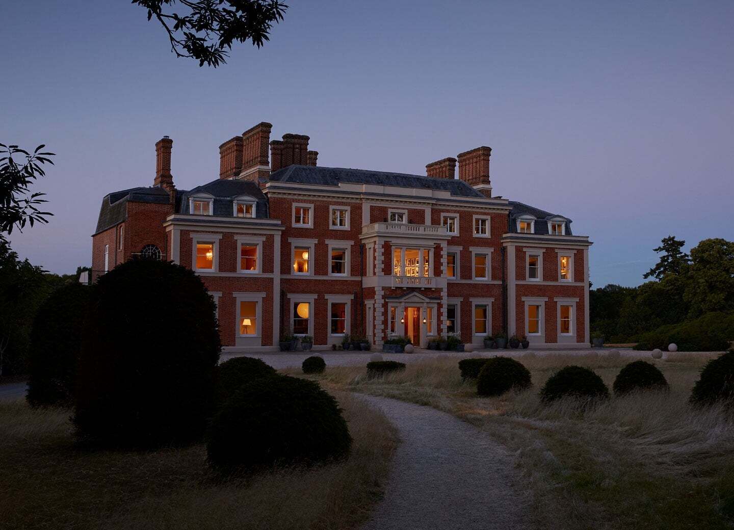The lit façade of Heckfield Place at twilight