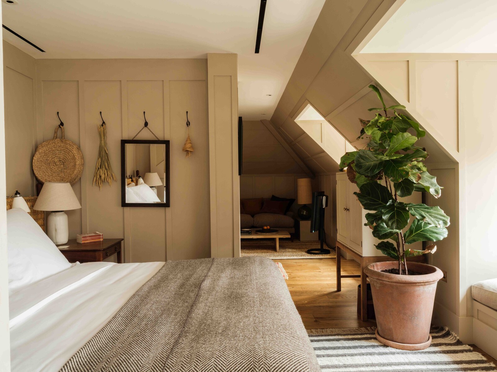 A guest room with board panelling and a potted fig