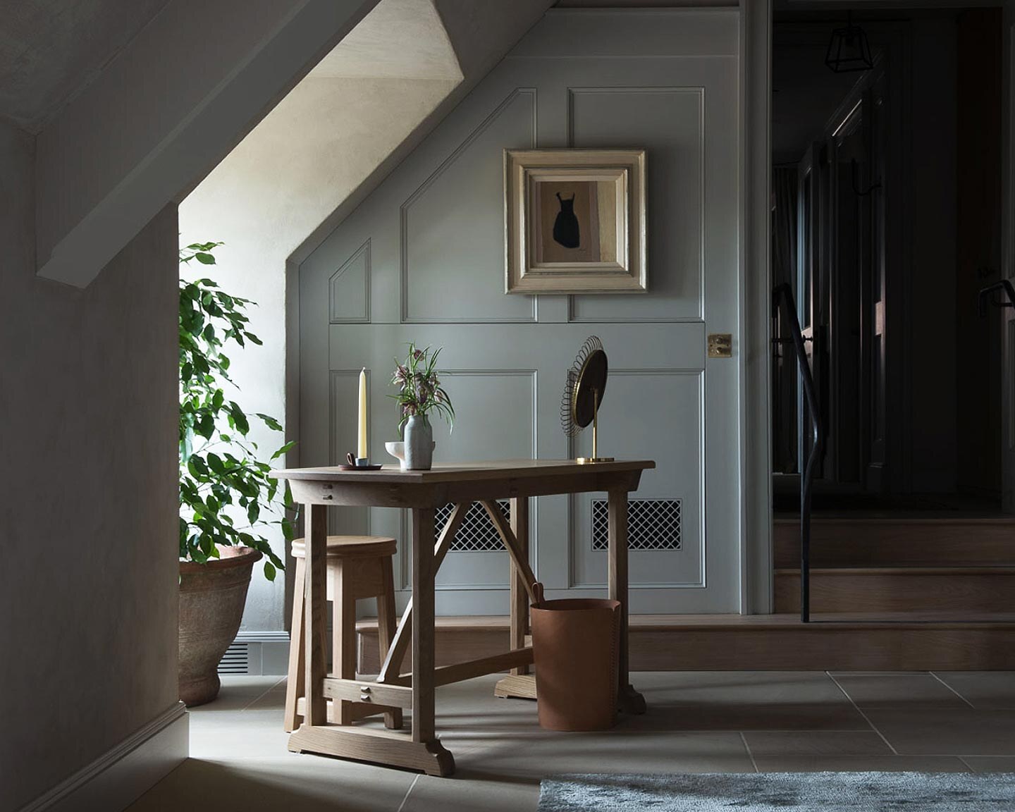 A panelled landing with a writing table and morning light