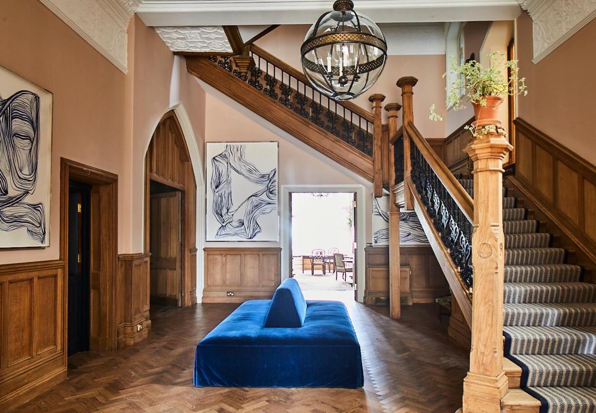Oakley Court &mdash; the panelled entrance hall with staircase and blue velvet bench