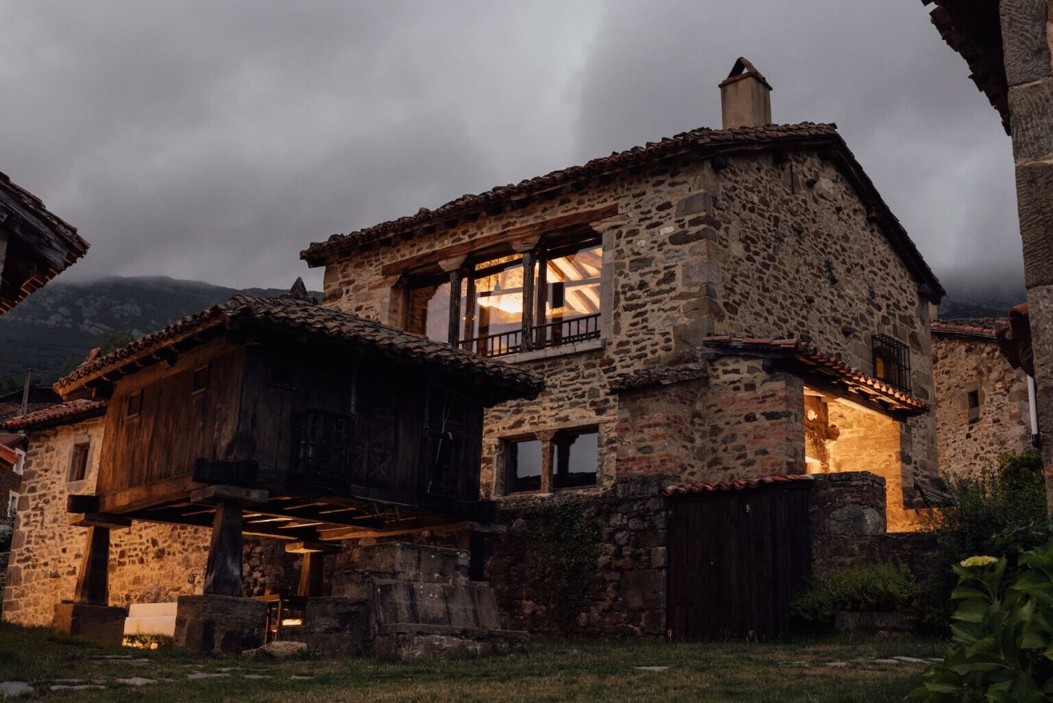 Solo Palacio — stone buildings and a raised Asturian hórreo at dusk