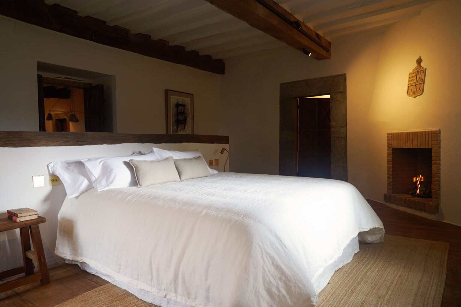 Solo Palacio — suite with white linen bed and a corner fireplace