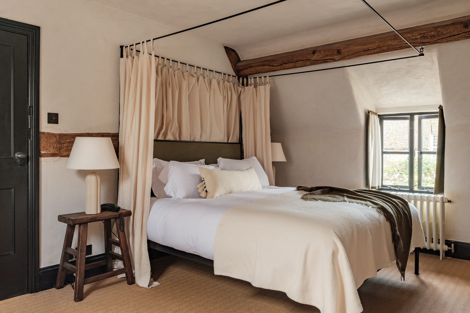 The Bull, Charlbury — a beamed bedroom with a linen-canopied four-poster bed