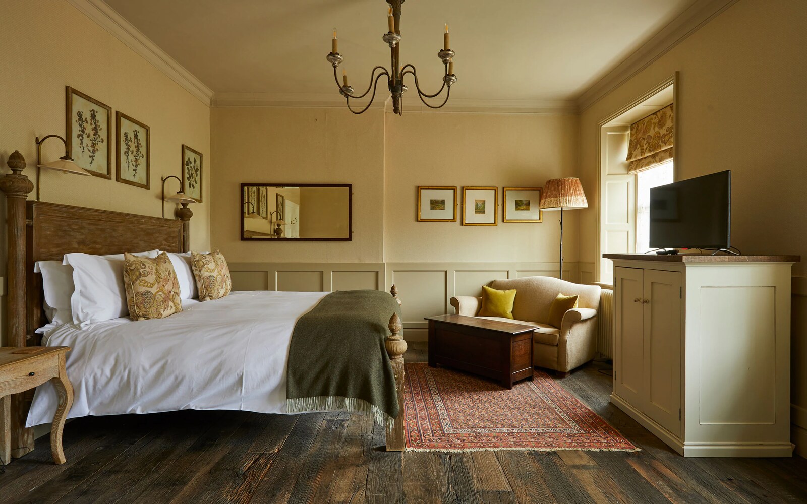 The Pig — a panelled bedroom with chandelier, sofa and botanical prints