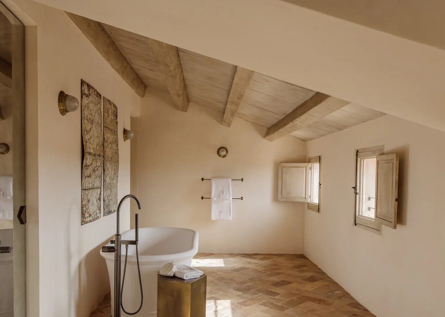 Vestige Son Vell — bathroom with a freestanding tub beneath sloping timber rafters