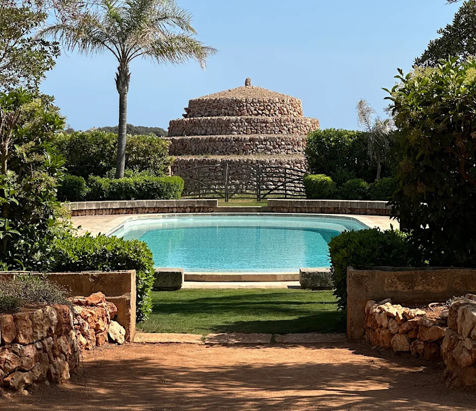 Vestige Son Vell — oval pool in the gardens with a prehistoric stone talayot behind
