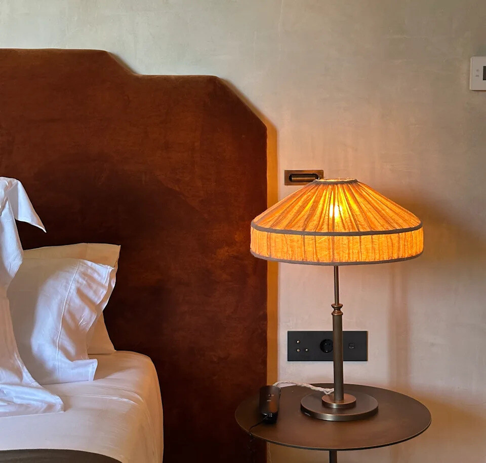 Vestige Son Vell — bedside detail with a pleated lamp and a velvet headboard