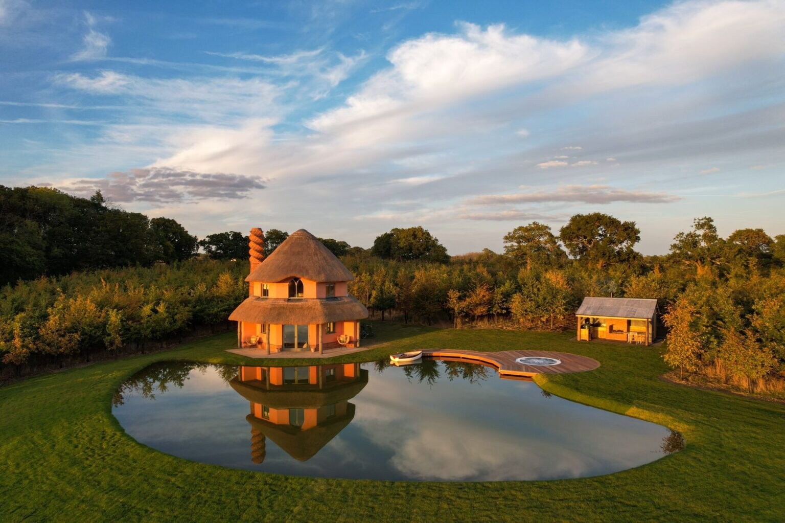 Wilderness Reserve — round thatched tower house reflected in its lake at sunset